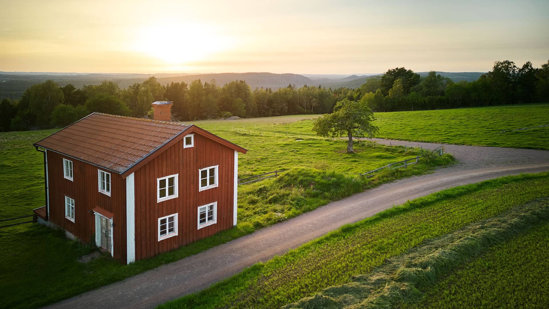 Rött hus med vita knutar med utsikt över det småländska höglandet.